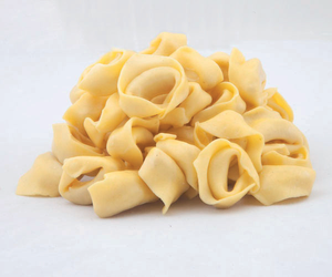 Mucchietto di pasta gialla cruda su sfondo bianco