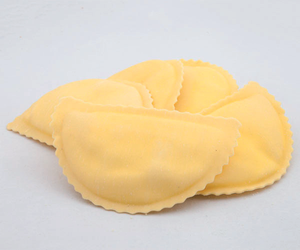 Ravioli gialli crudi su sfondo bianco