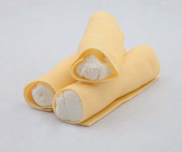 Tre cialde arrotolate ripiene di crema su uno sfondo chiaro