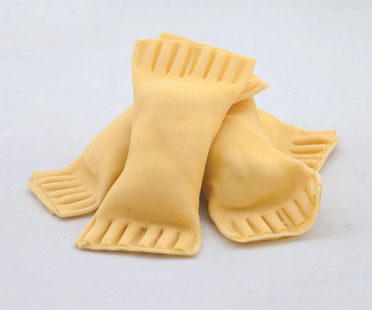 Tre fagottini di pasta sfoglia cruda con bordi ondulati su sfondo bianco.