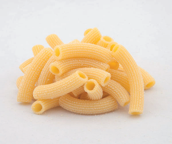 Pila di pasta di maccheroni cruda a gomito su sfondo bianco