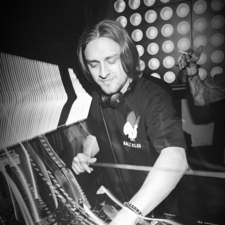 DJ mit langen Haaren und Kopfhörern in einem Club, beim Mixen von Musik. Schwarzweißfoto.