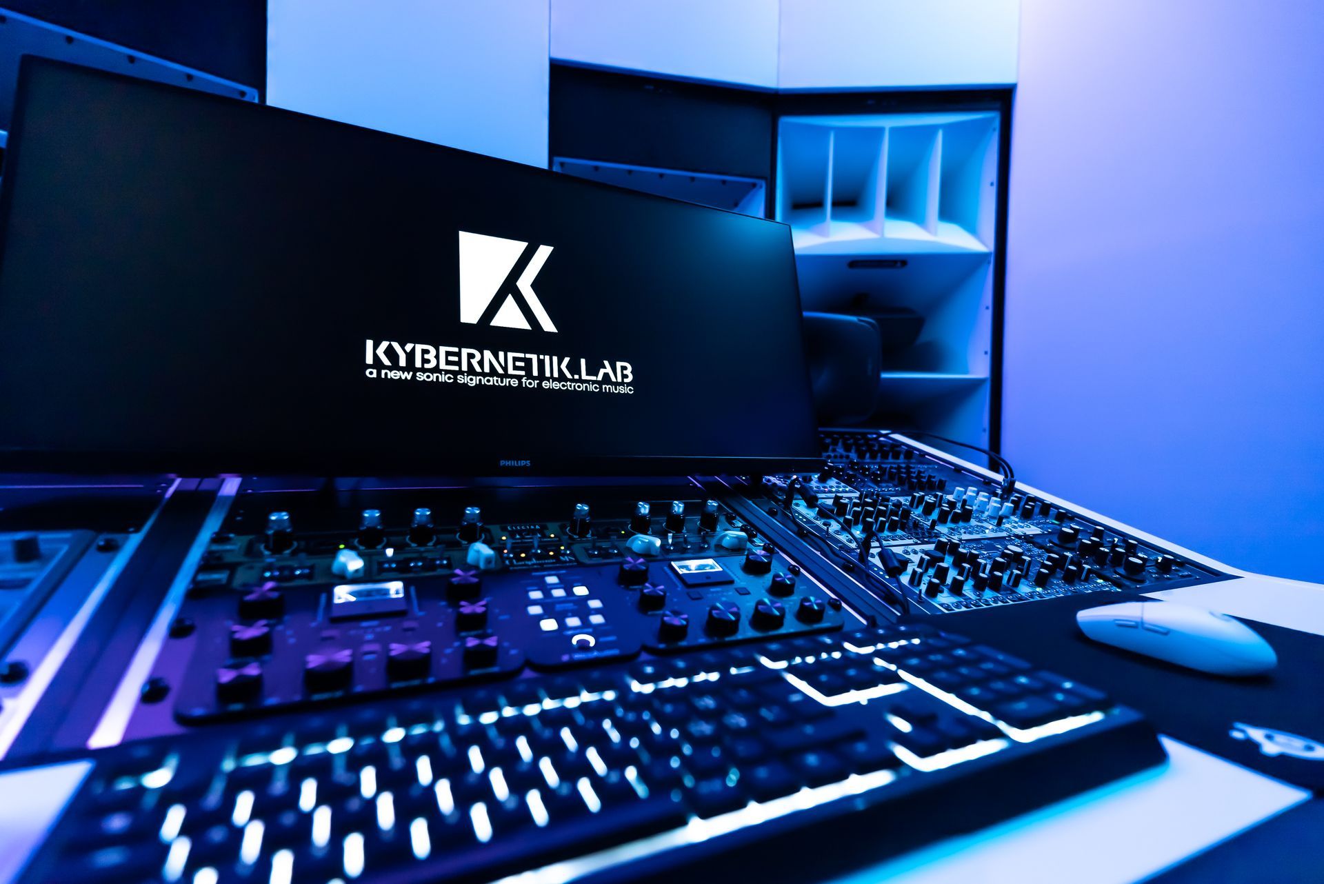 Blau beleuchteter Gaming-Schreibtisch mit Monitor, Tastatur, Mischpult und Maus in einem modernen Setup
