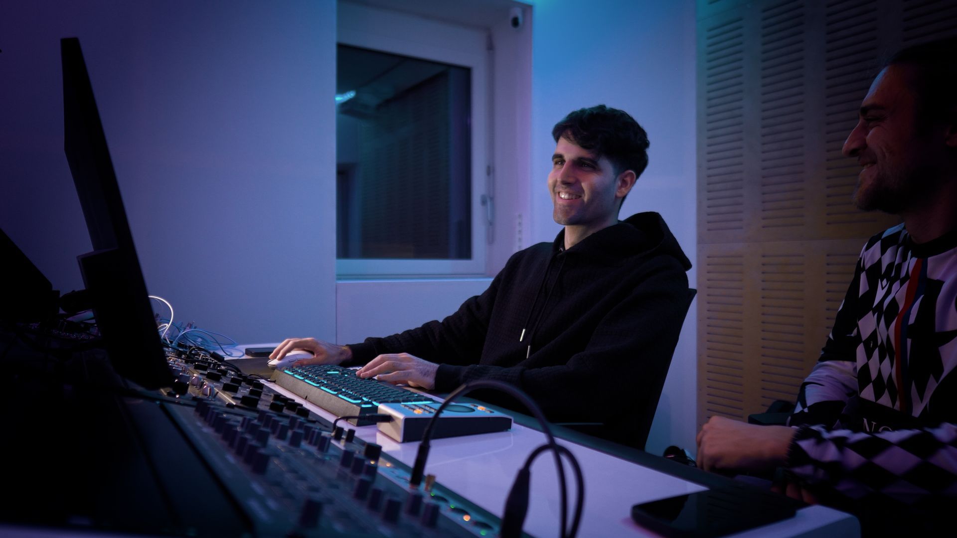 A man in a music studio smiling and operating the studio.
