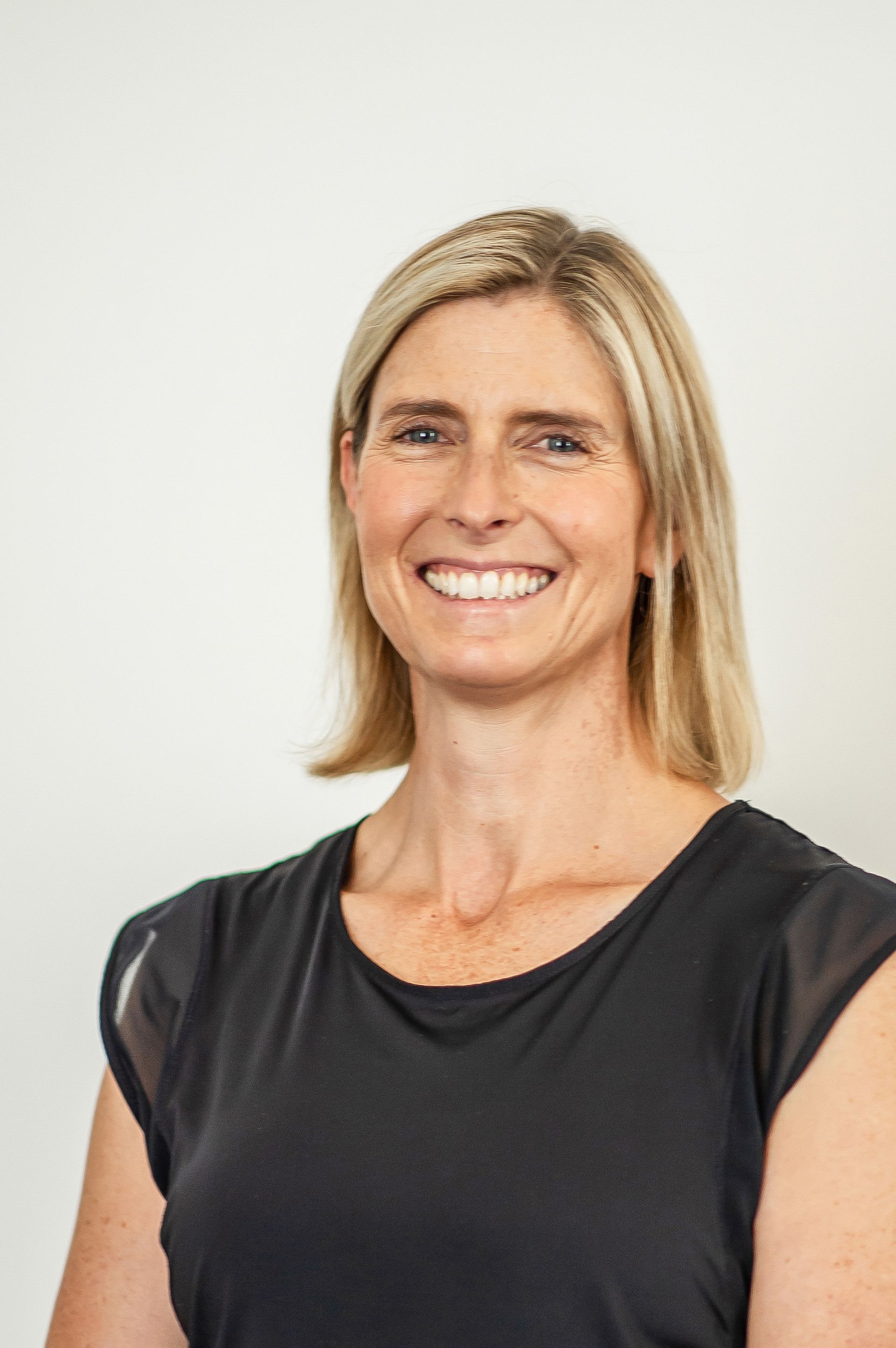 A woman in a black shirt is smiling for the camera.