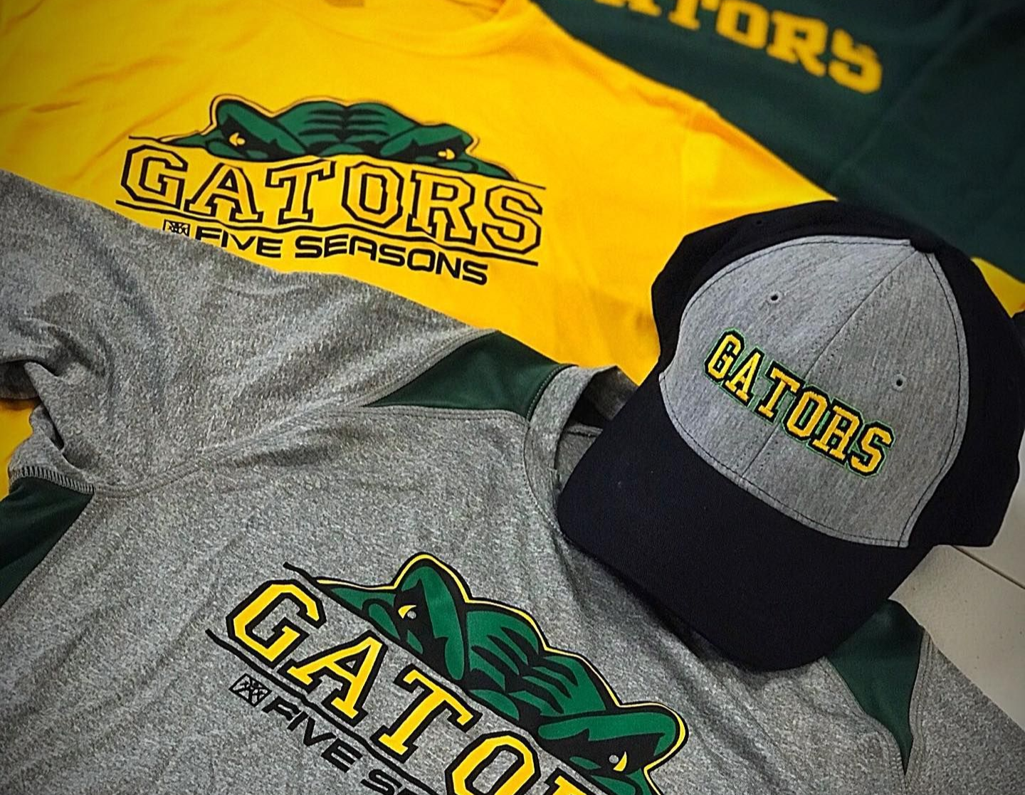 Gators team shirts and caps in yellow, gray, and black with logo design