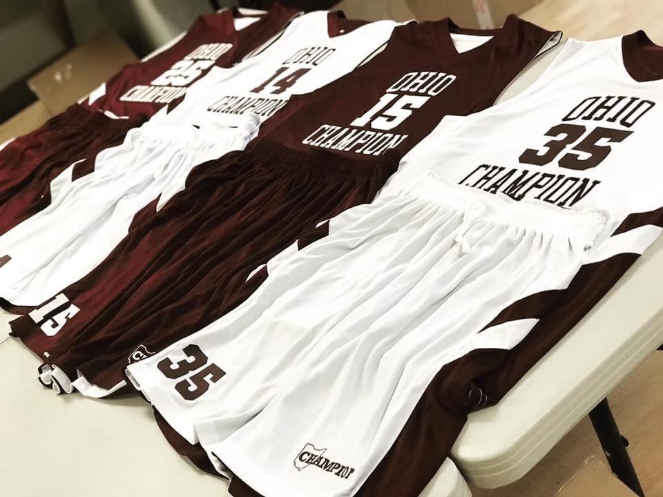 Ohio basketball jerseys laid out on a table, white and maroon with player numbers and names.