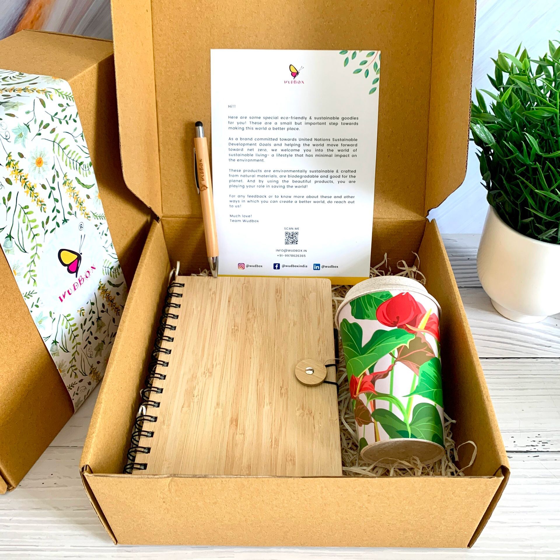 A cardboard box filled with a notebook a cup and a pen