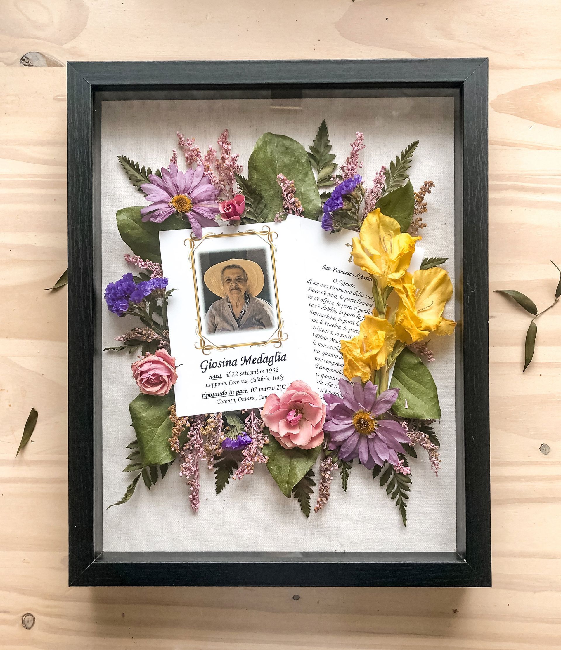 A picture of a man in a hat is surrounded by flowers and leaves in a frame.
