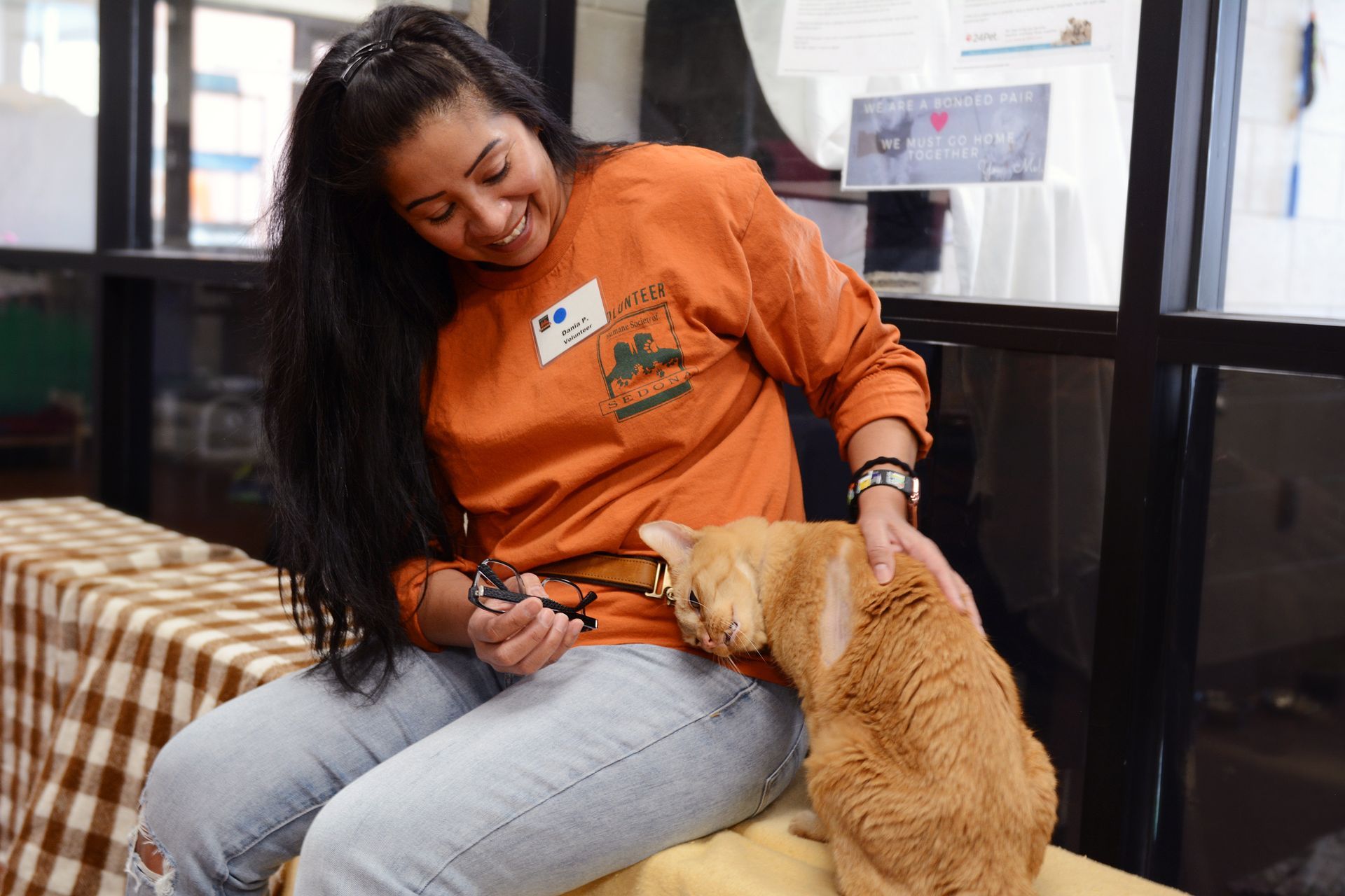 A woman is sitting on a bed with a cat on her lap.
