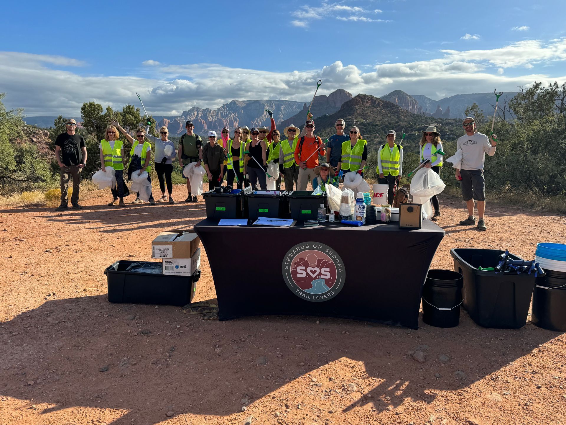 A group of people are standing around a table with mountains in the background.