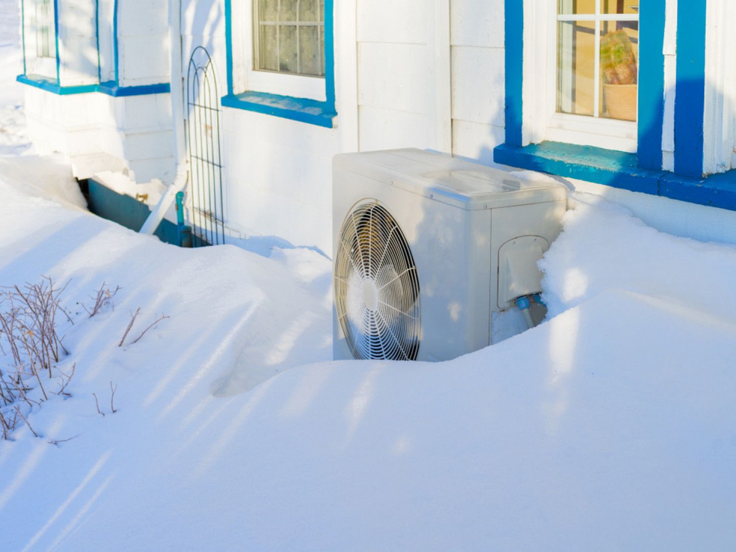 A snow-covered white house with blue trim, creating a picturesque winter scene.