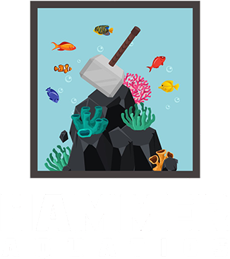 Thor's hammer rests on a rocky reef, surrounded by colorful fish and coral in a blue aquarium.
