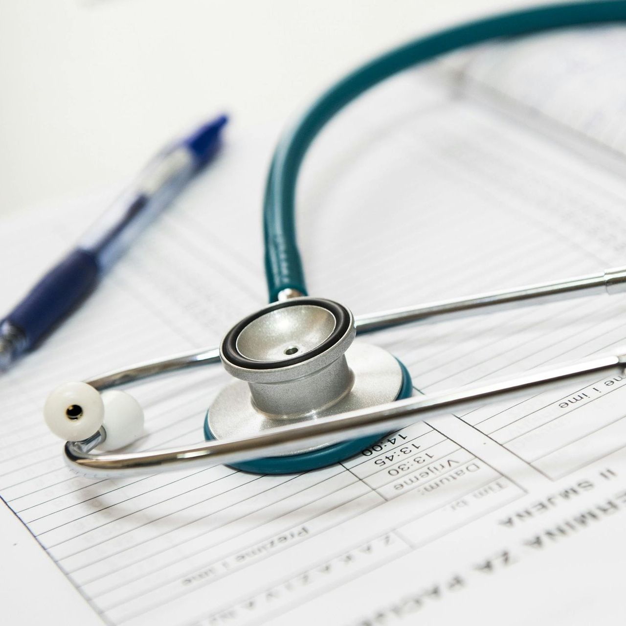 Stethoskop und Stift auf medizinischen Unterlagen, was Gesundheitsversorgung und Untersuchung bedeutet.