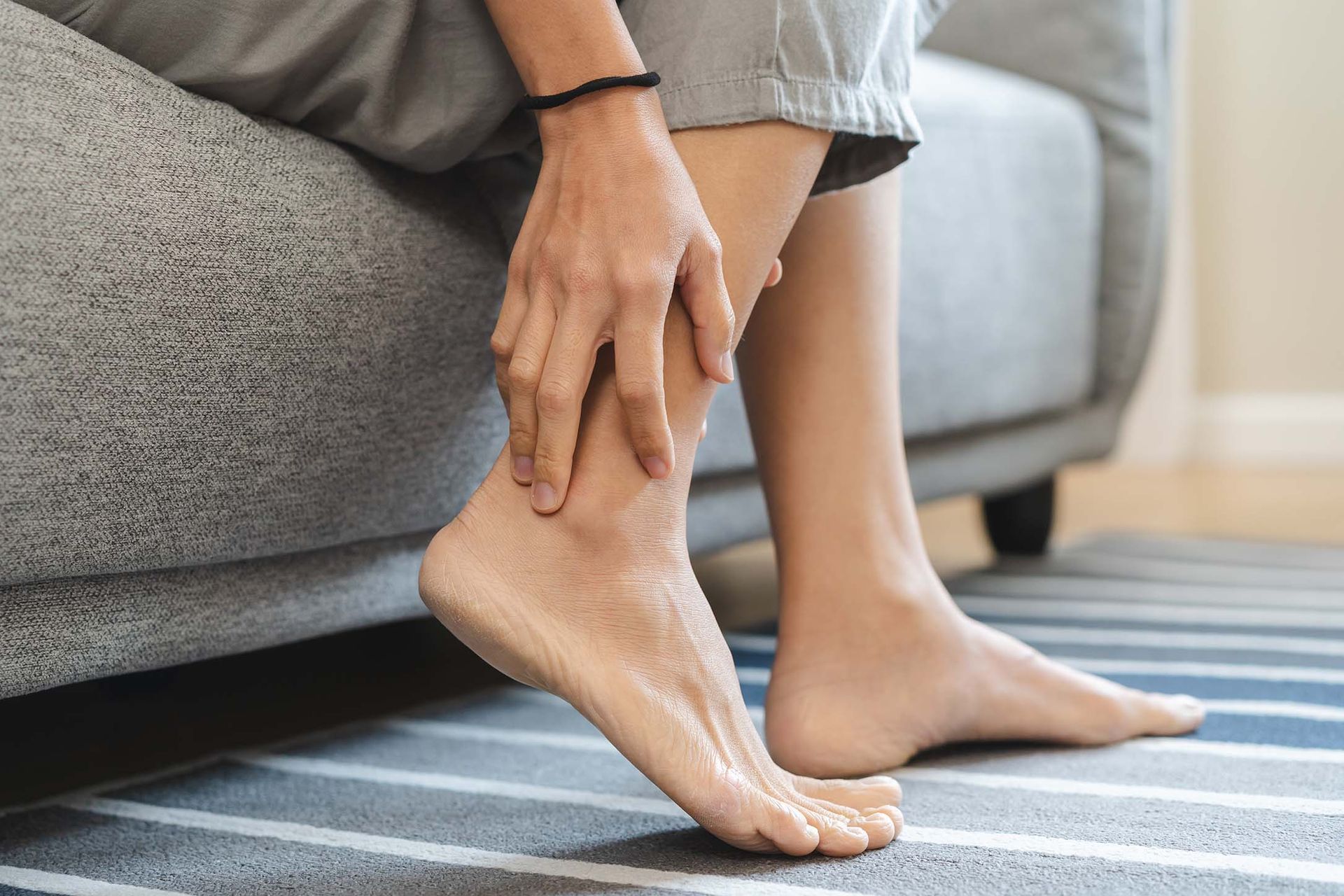 Person sitzt und hält sich den Fußknöchel