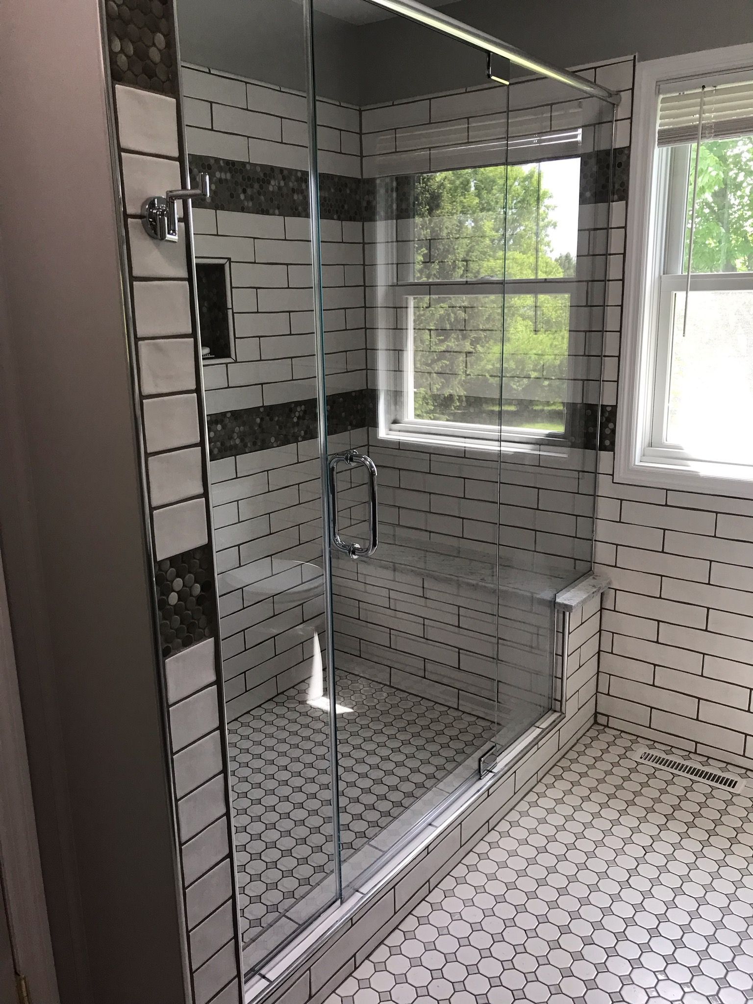 A bathroom with a walk in shower and a window.