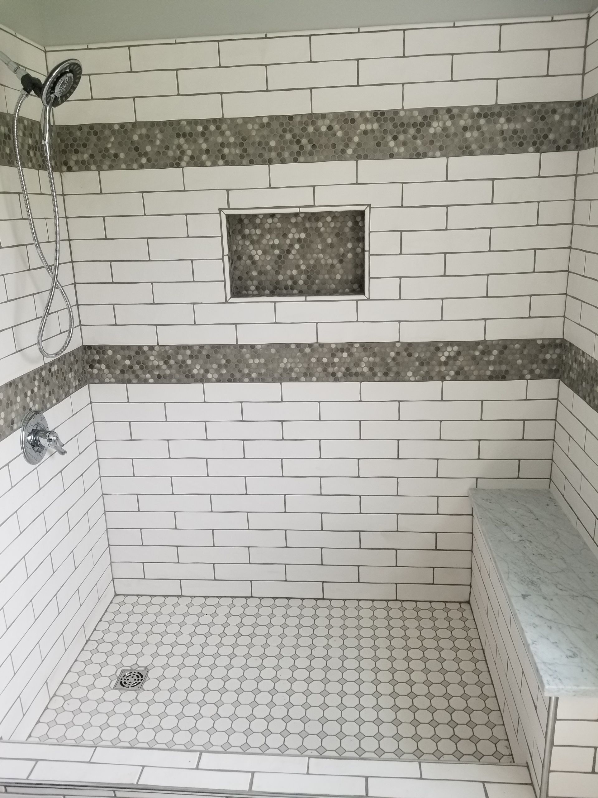 A shower with a bench and a shower head