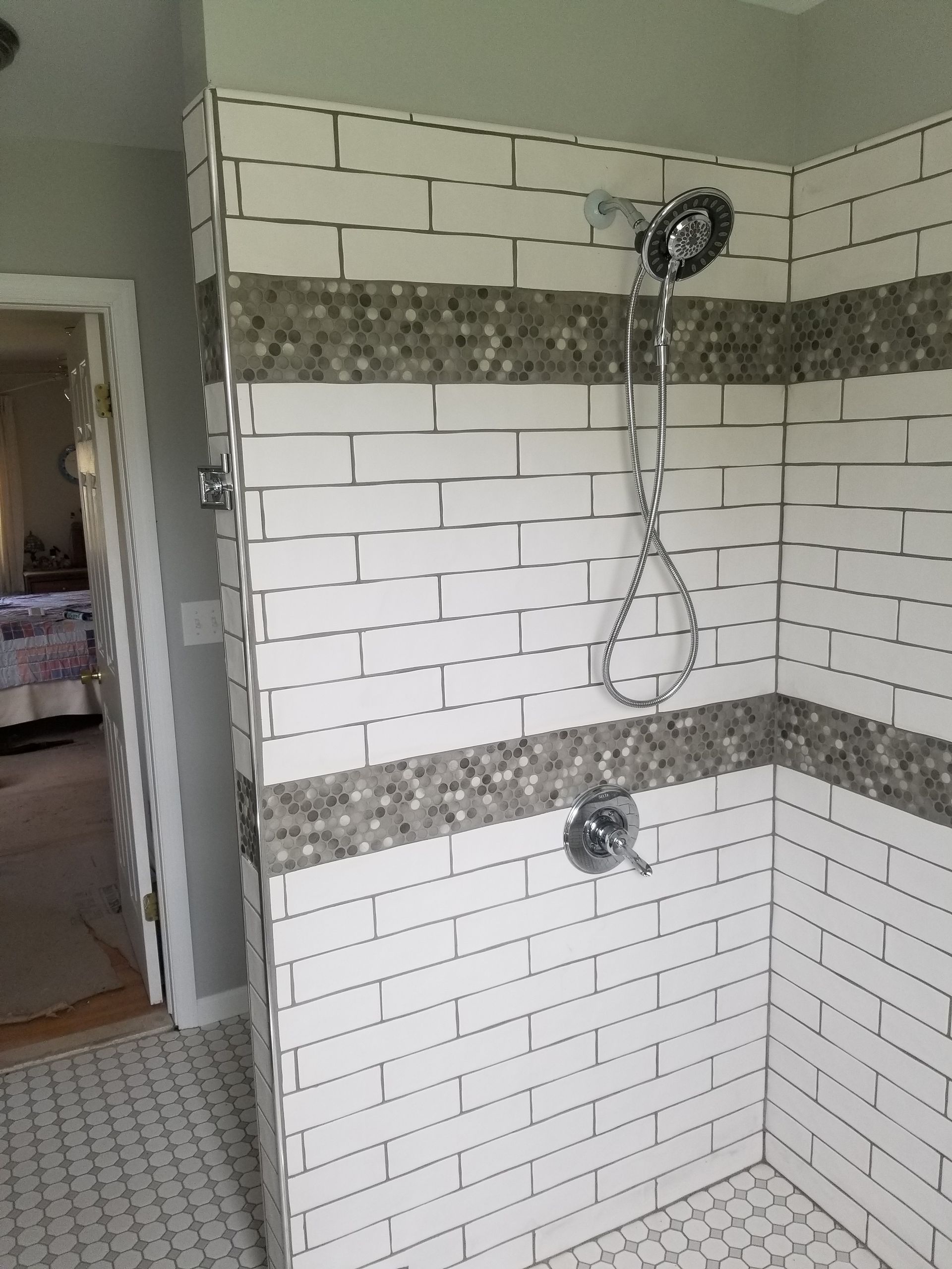 A bathroom with white brick walls and a walk in shower.