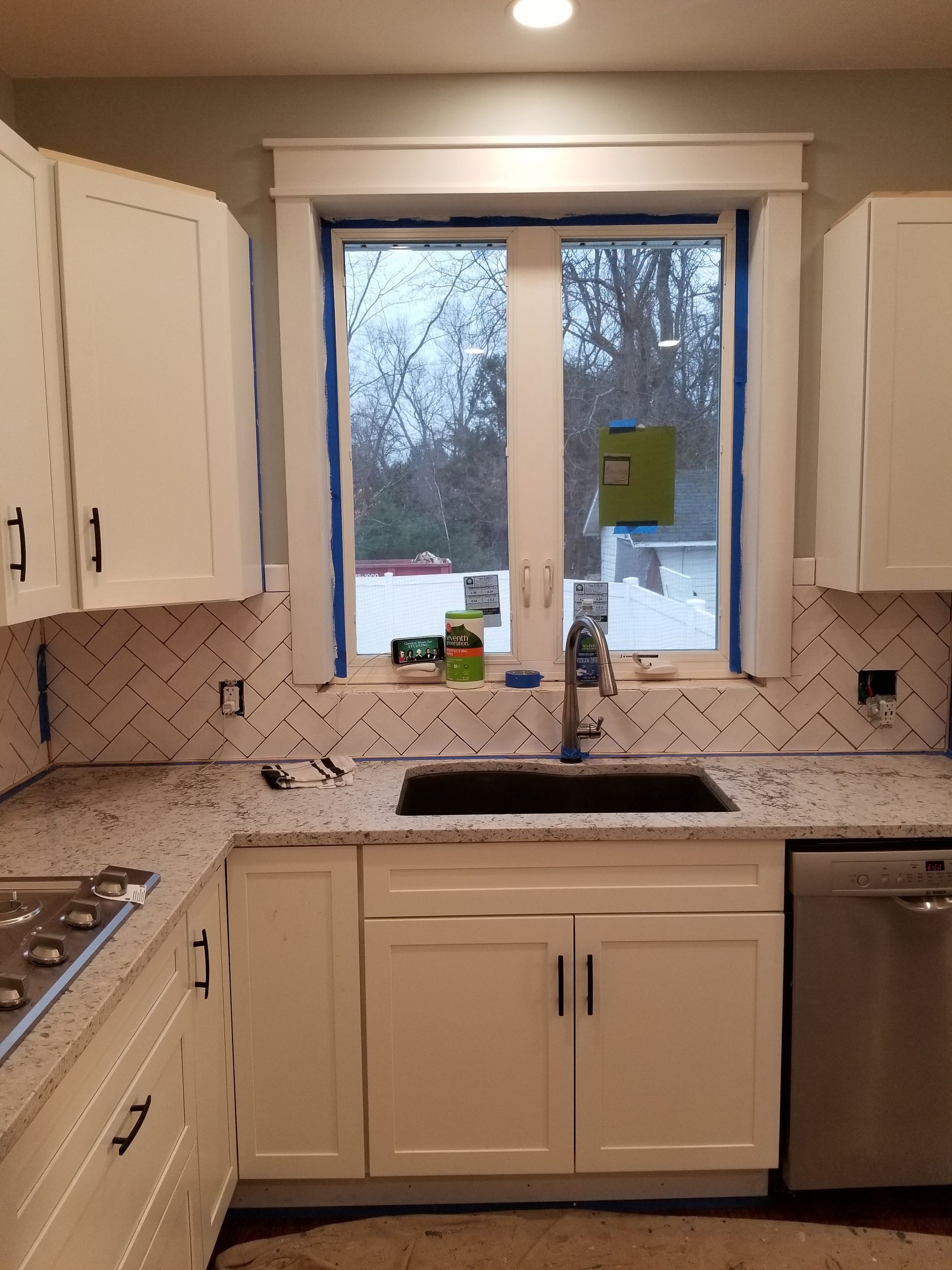 A kitchen with white cabinets a sink and a window