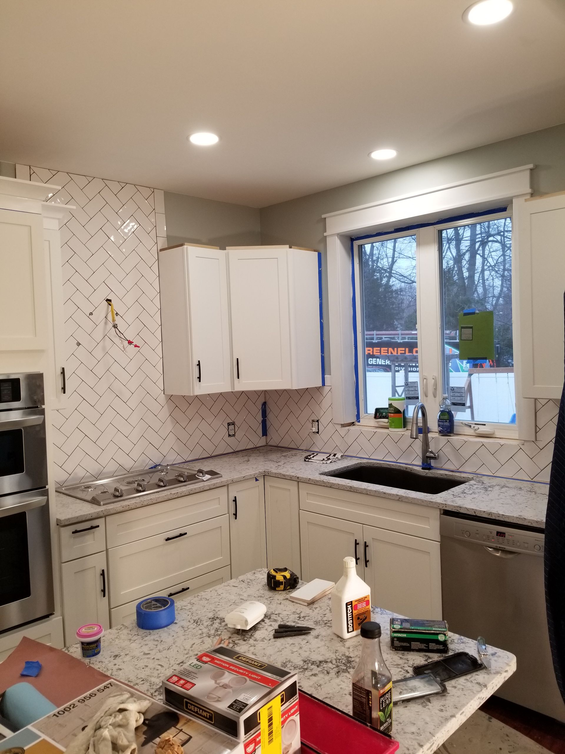 A kitchen with white cabinets , granite counter tops , a sink , and a window.