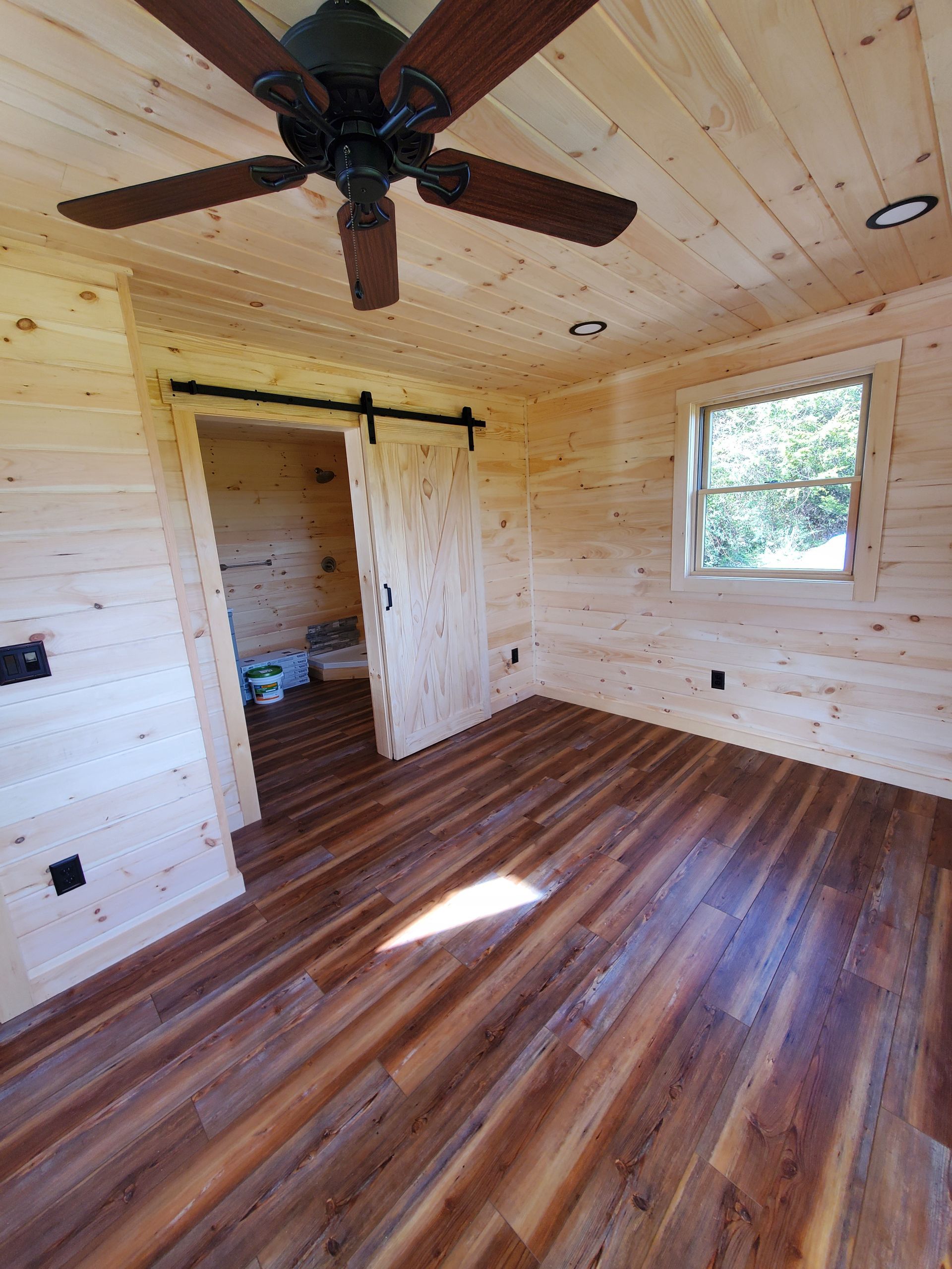 There is a ceiling fan in the room and a sliding barn door.