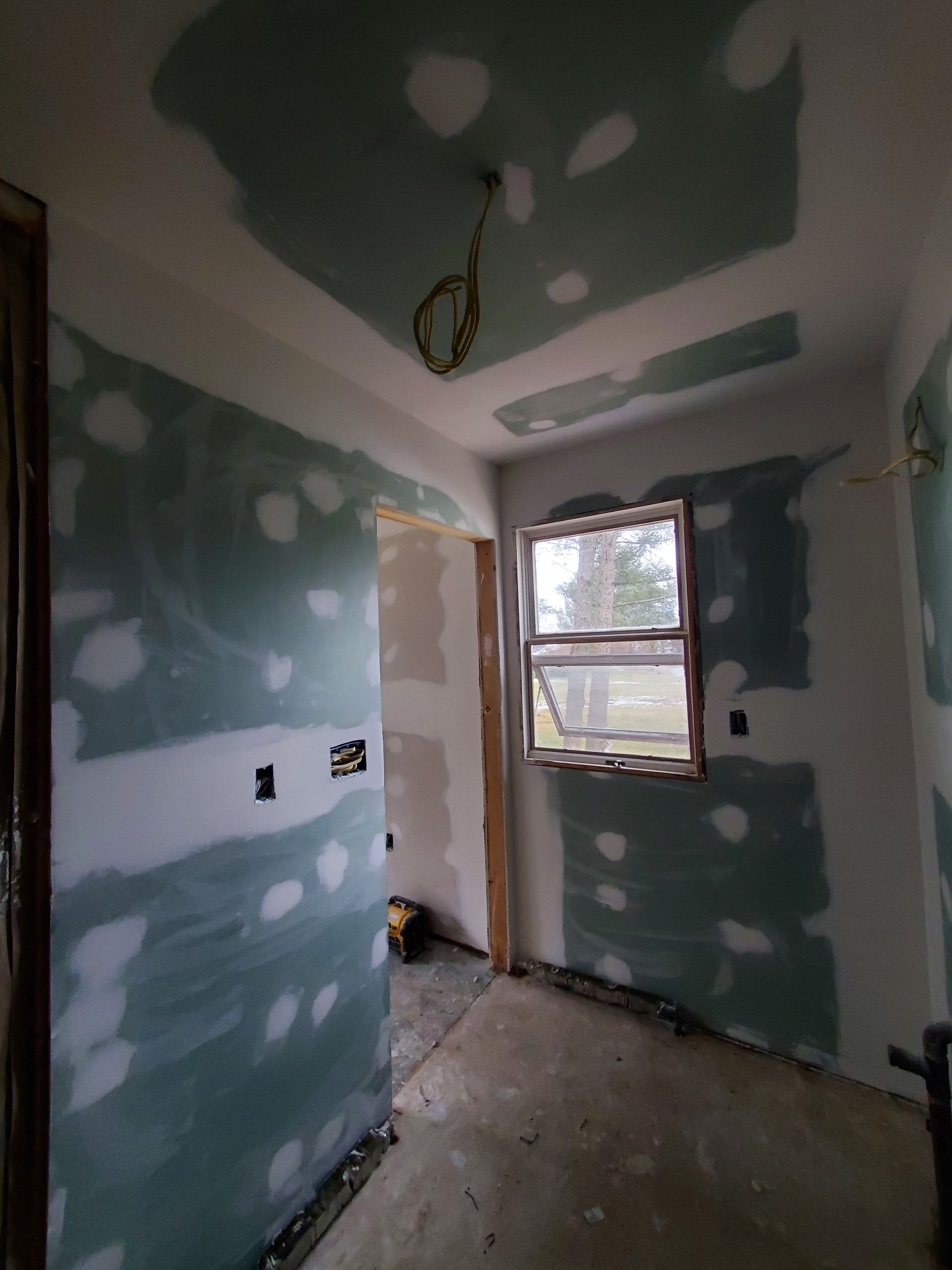 A room with a window and drywall on the walls