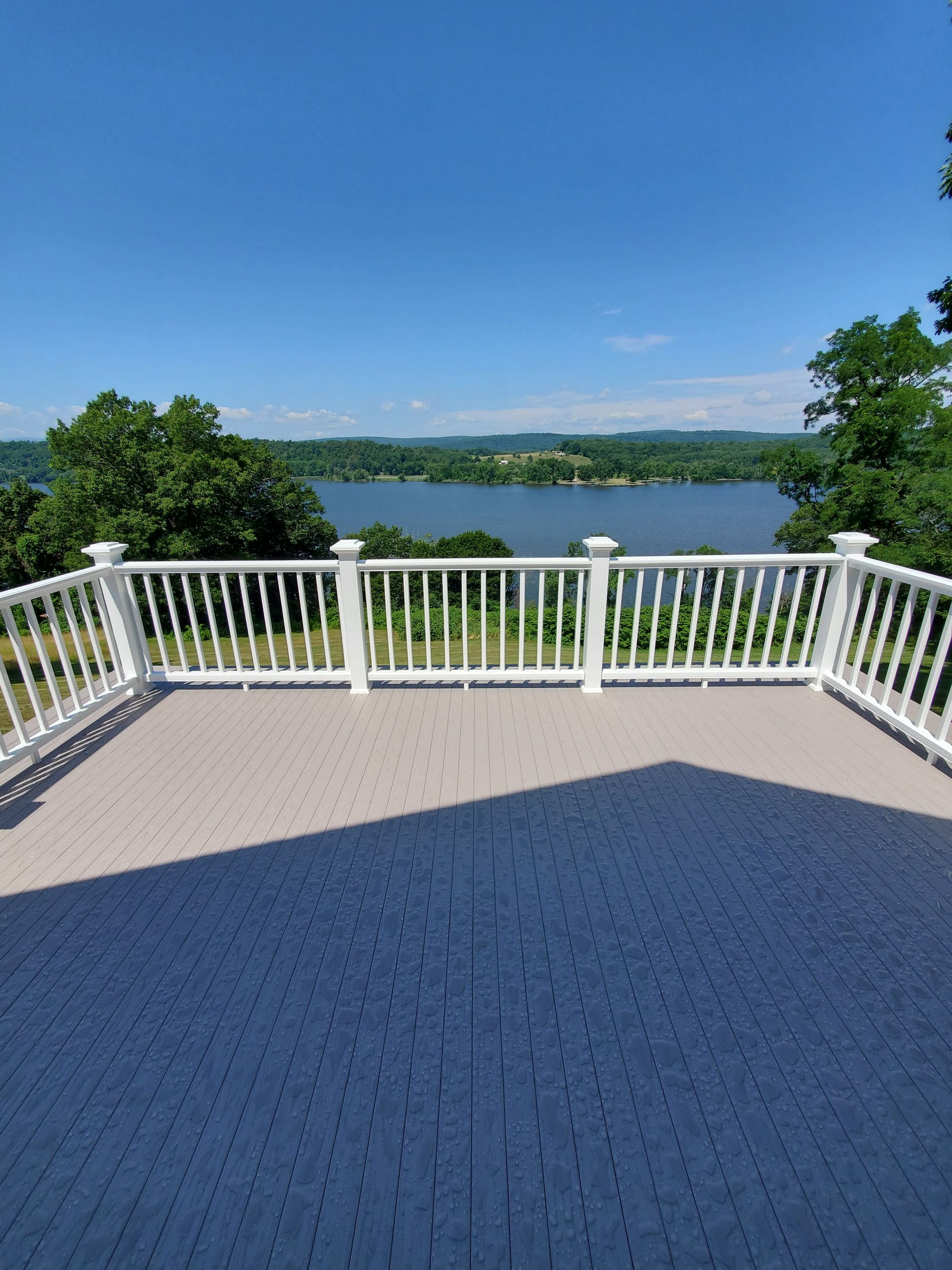 A large deck with a view of a lake and trees