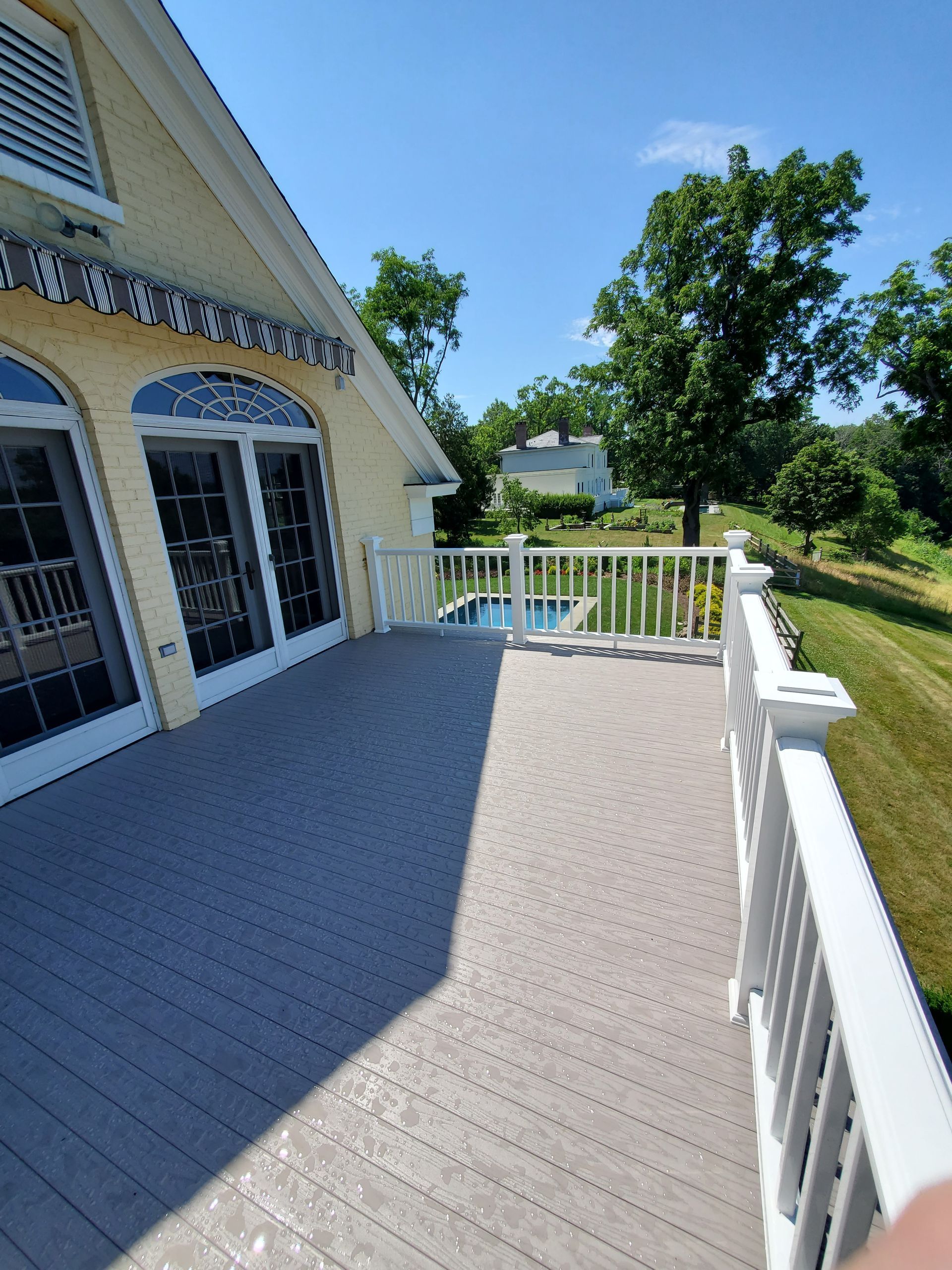 A large deck with a white railing and sliding glass doors
