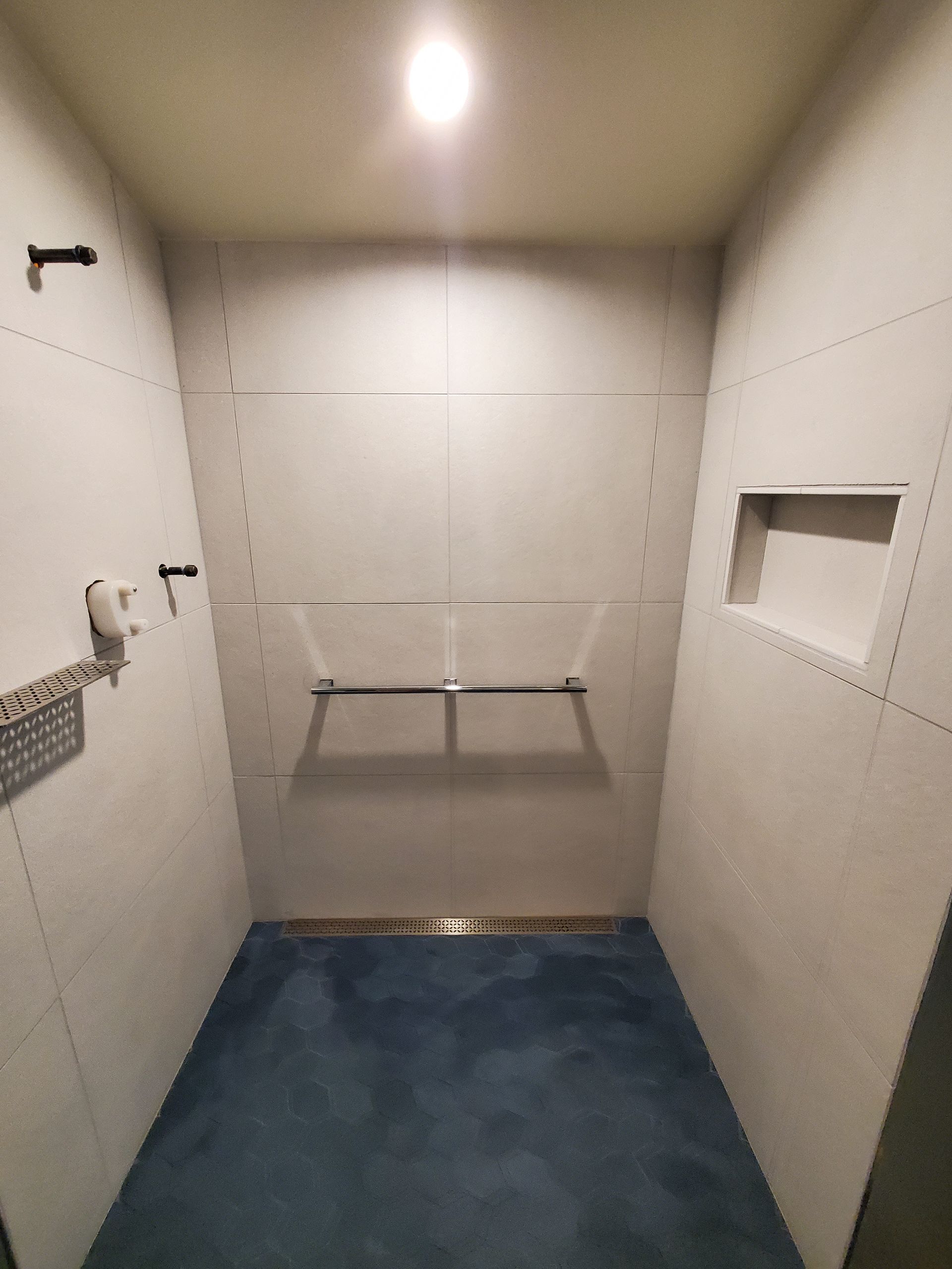 A bathroom with a walk in shower and a blue floor.