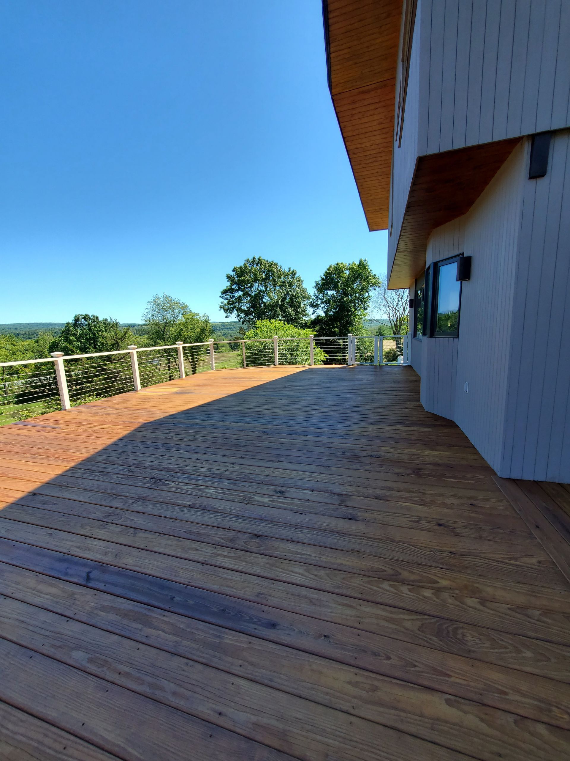 A wooden deck leading to a house with trees in the background