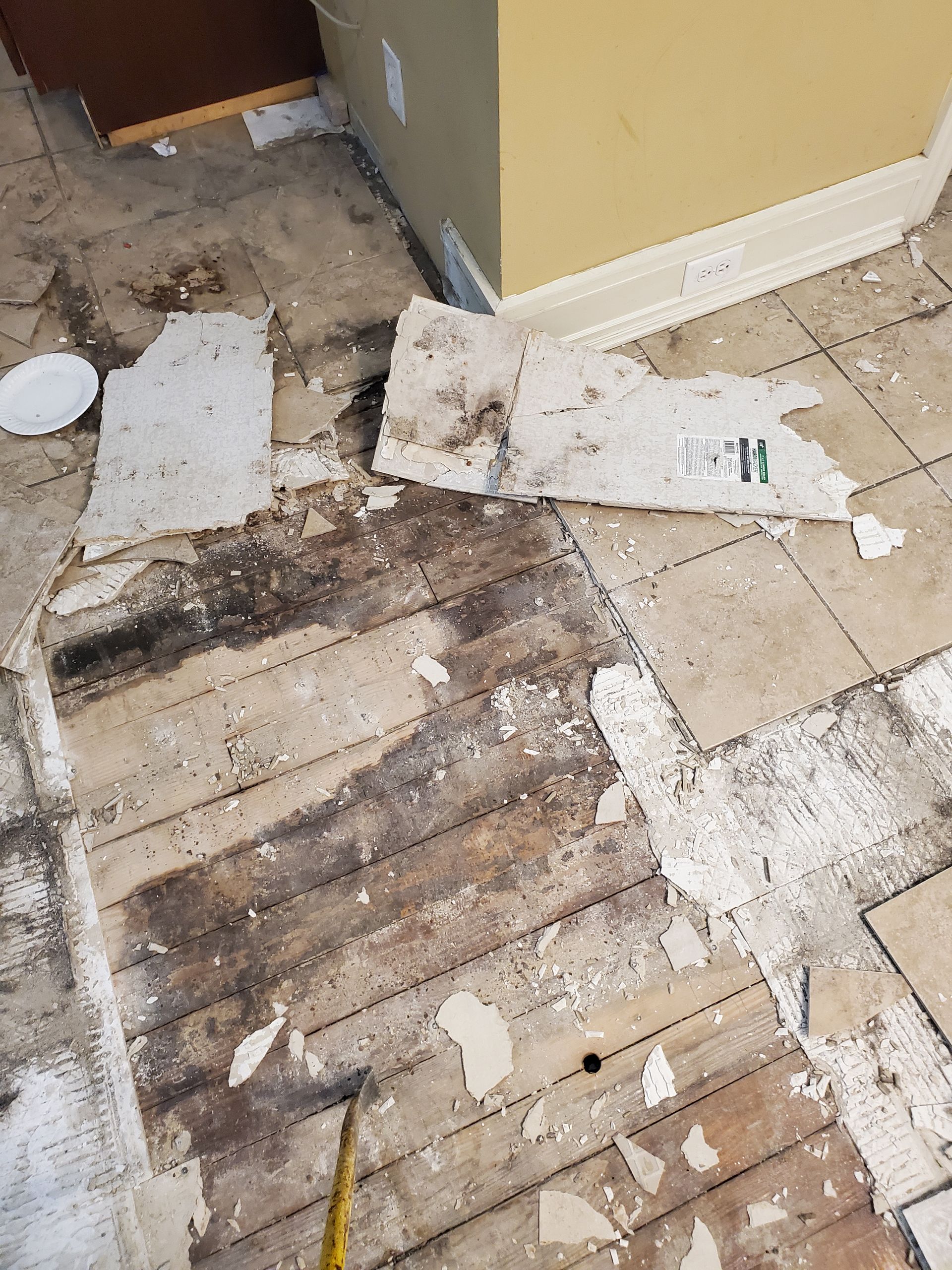 A hammer is laying on a wooden floor in a room.