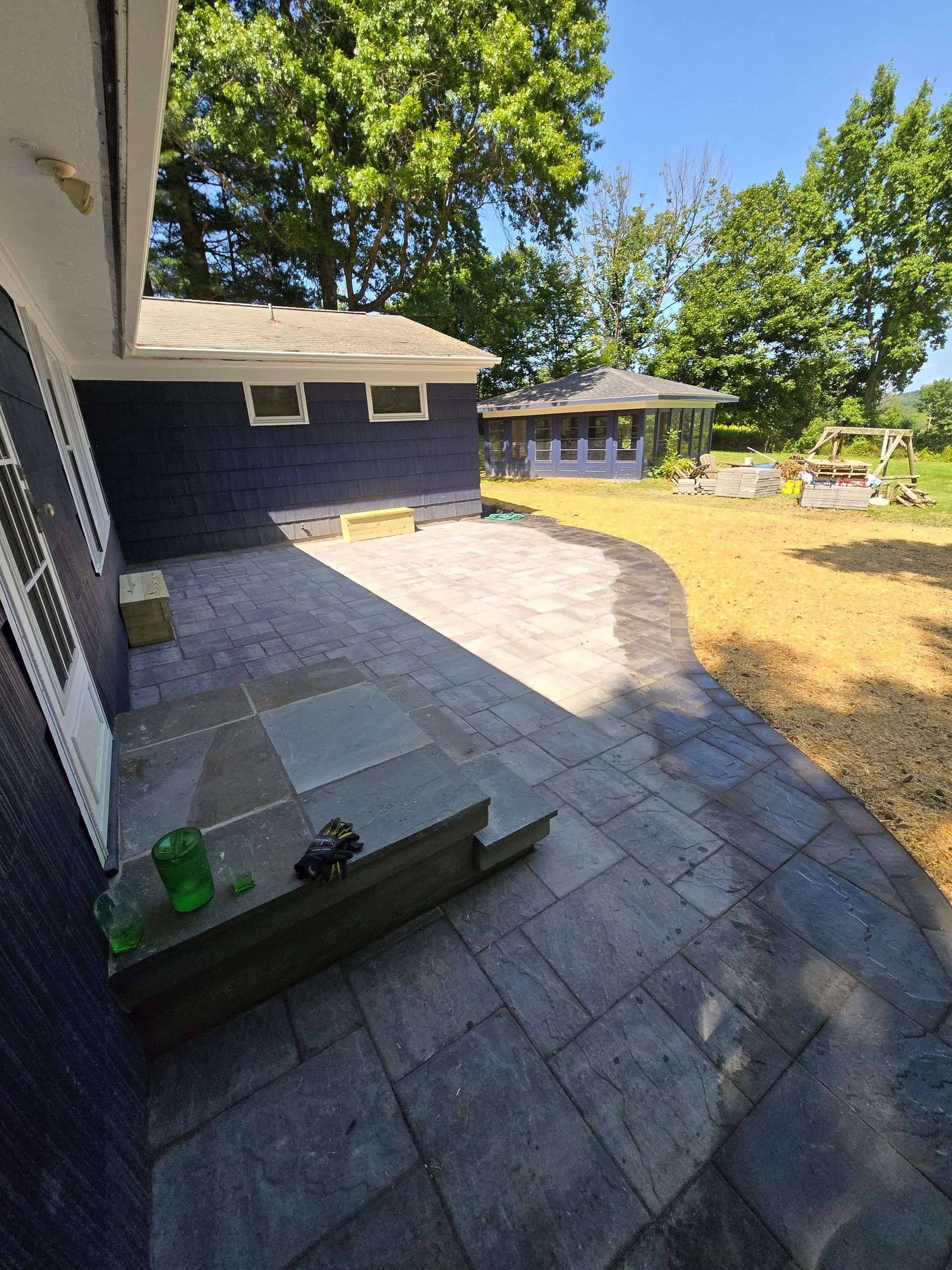A house with a patio in front of it and trees in the background.