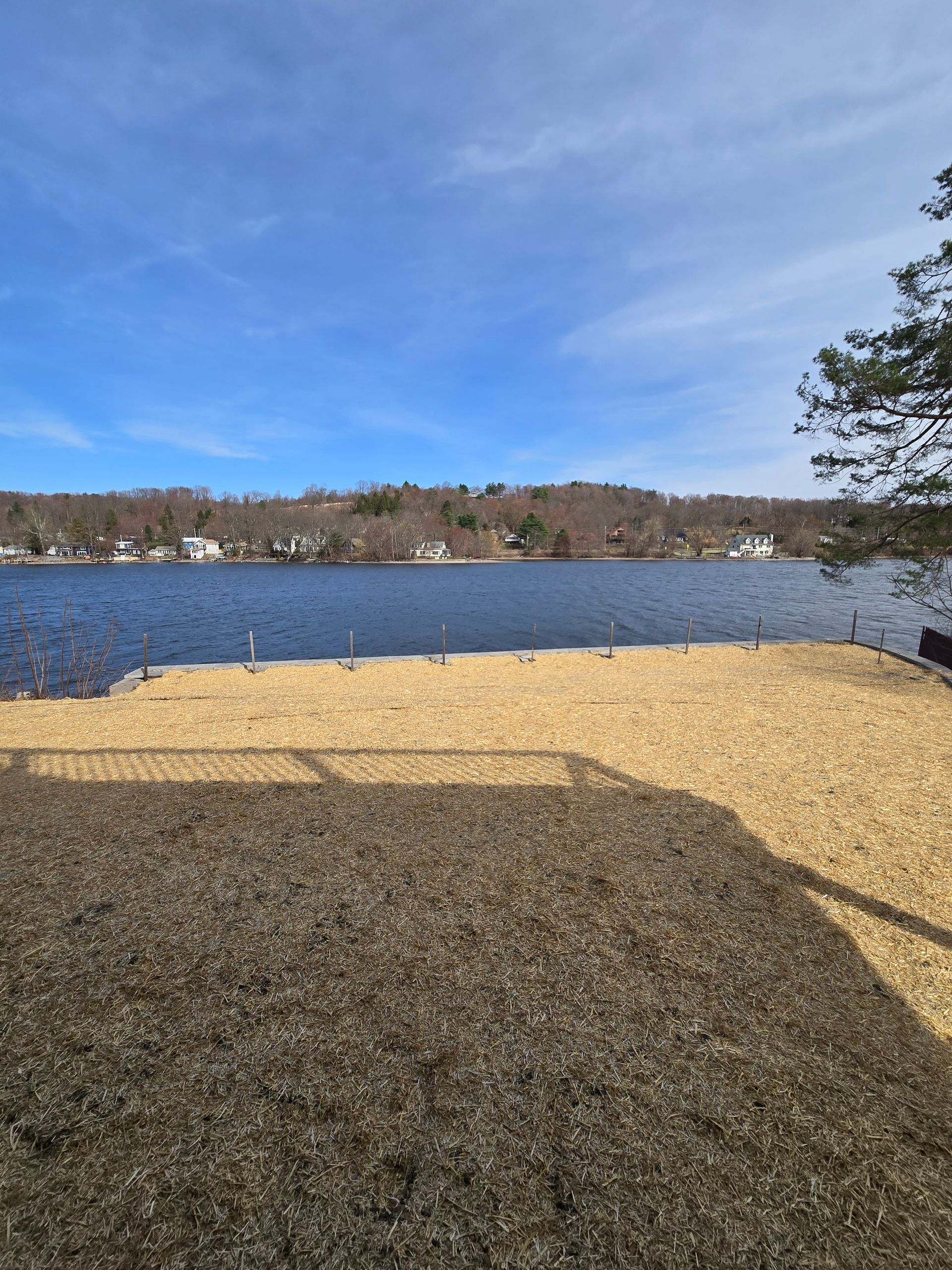 A sandy beach next to a lake on a sunny day.