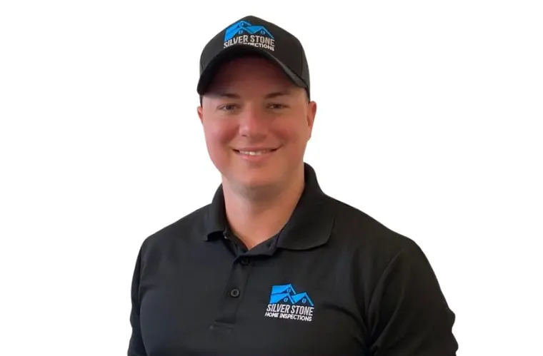 A man wearing a black polo shirt and a black hat is smiling for the camera.