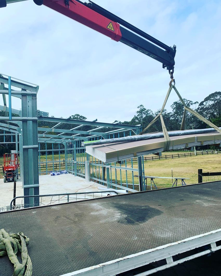 A Crane Lifts Panels for A Steel-Framed Barn Under Construction in A Field — Express Timber Solutions In Long Jetty, NSW