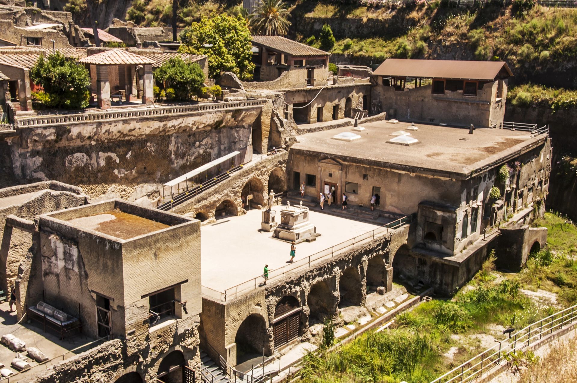 Antichi edifici in pietra su una collina con archi, tetti piani e un cortile soleggiato in un insediamento rurale