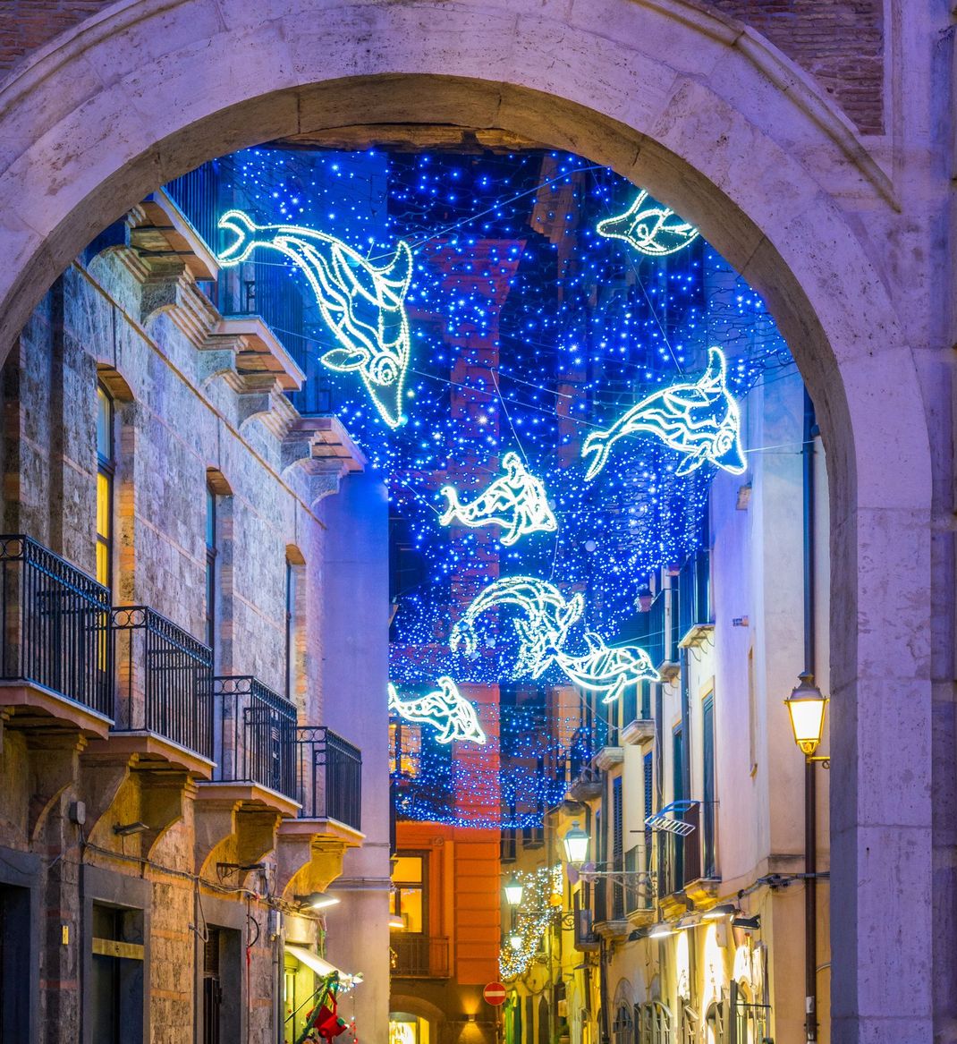 Stretta via europea illuminata di notte da scintillanti luci natalizie.
