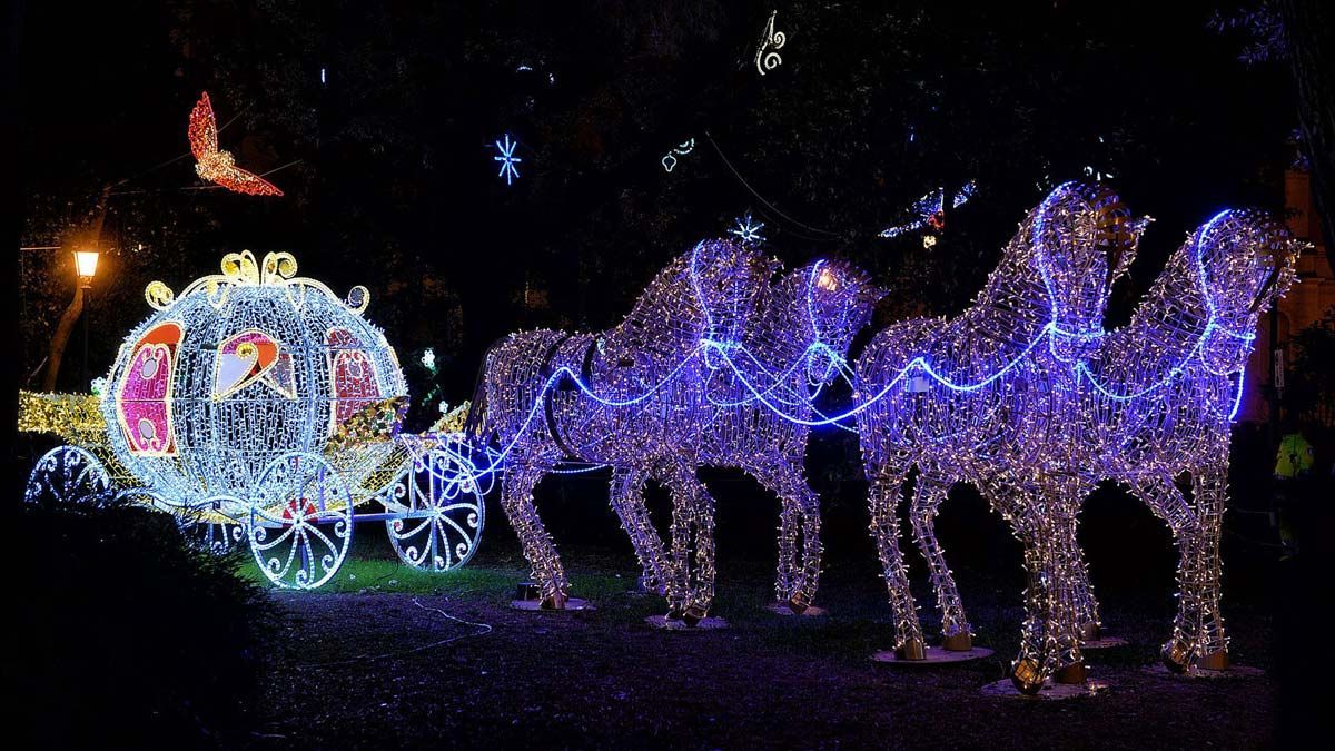 Spettacolare allestimento natalizio illuminato con figure di cavalli viola che trainano una carrozza decorata, di notte.