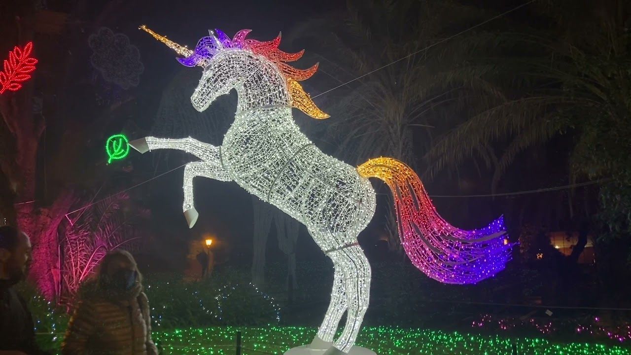 Scultura luminosa di unicorno che si erge di notte con criniera e coda arcobaleno
