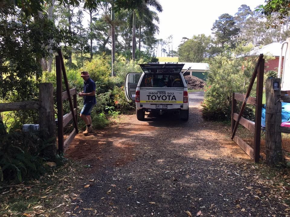 A Man Is Standing Next To A Toyota Truck Parked On A Dirt Road — Robon Electrical In Holloways Beach, QLD
