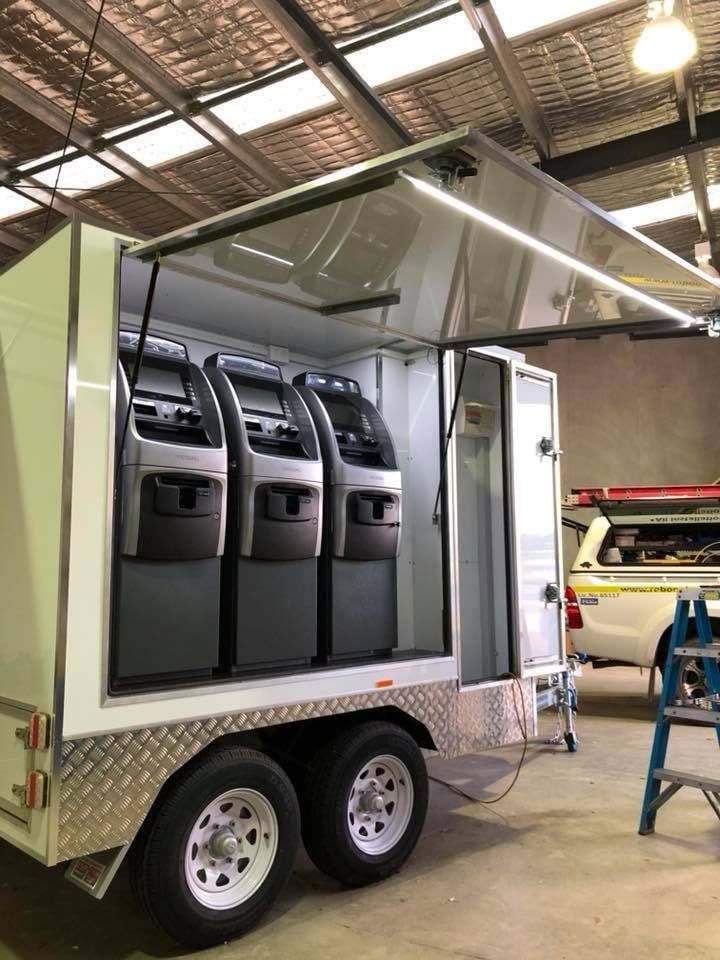A Trailer With Atm Machines Inside Of It Is Parked In A Garage — Robon Electrical In Holloways Beach, QLD