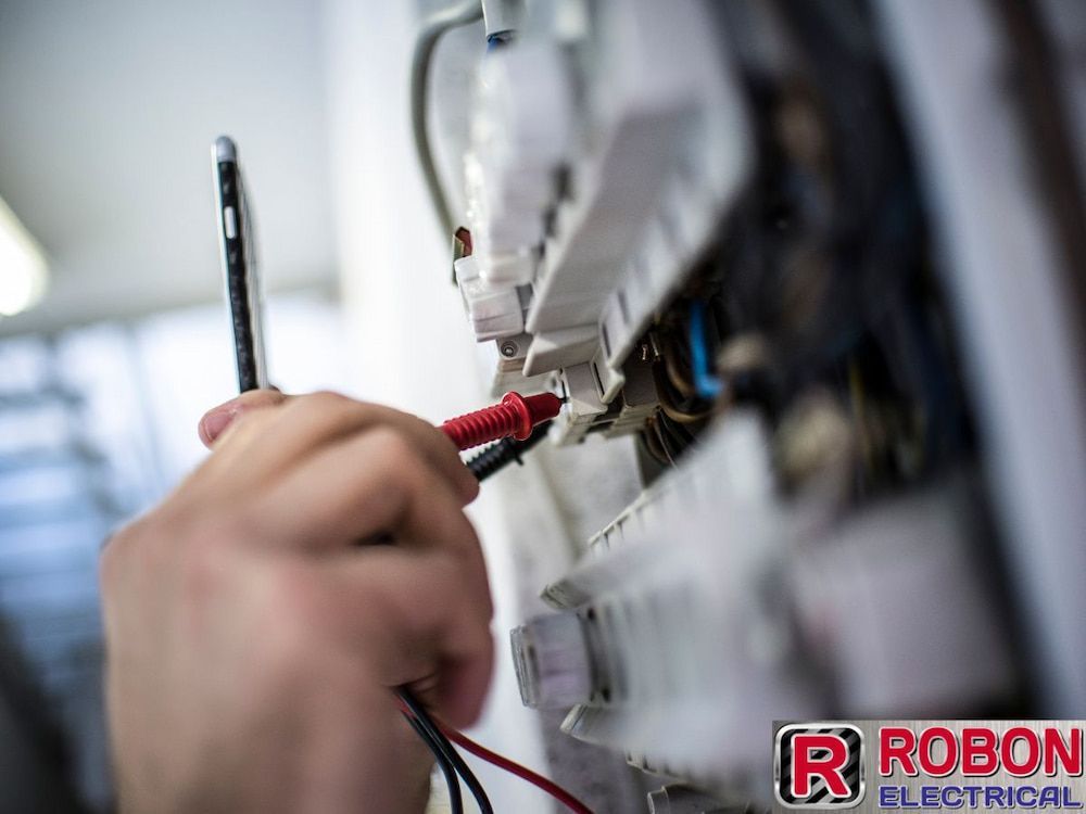 A Person Is Using A Multimeter To Test An Electrical Circuit — Robon Electrical In Holloways Beach, QLD