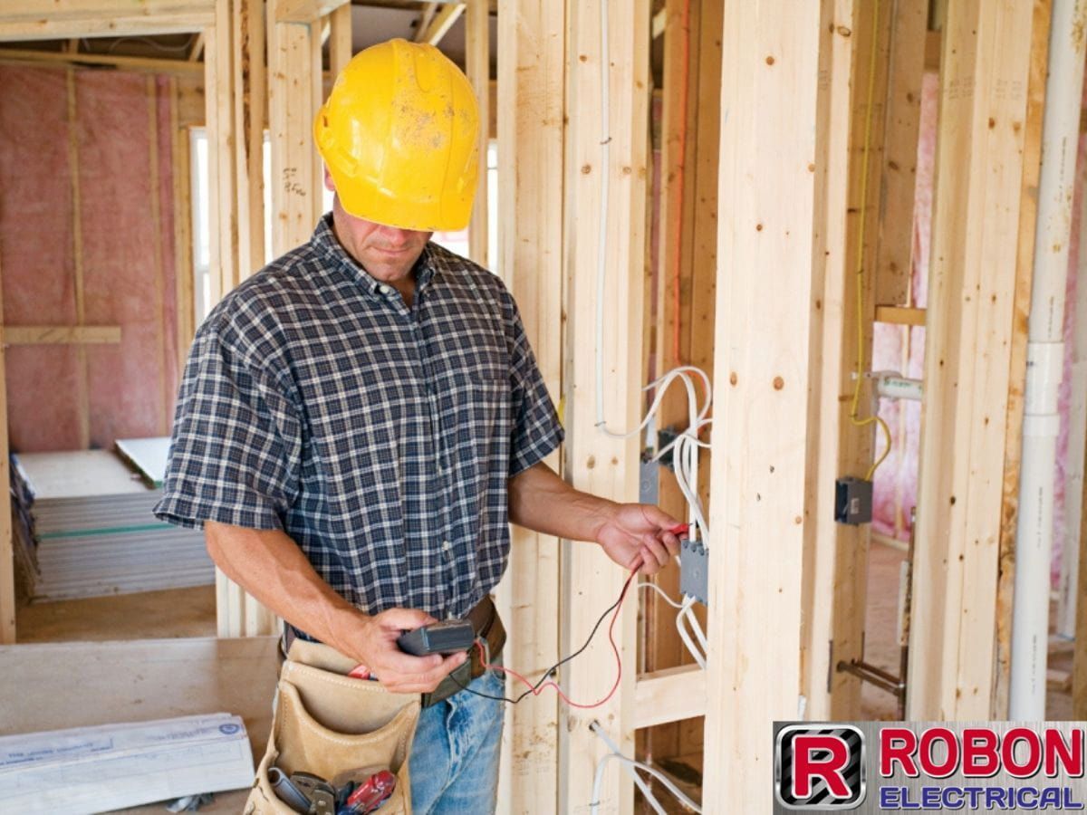 A Man Wearing A Hard Hat Is Working On Electrical Wires — Robon Electrical In Holloways Beach, QLD
