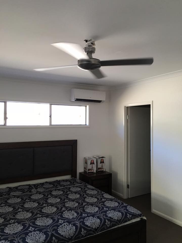 A Bedroom With A Bed And A Ceiling Fan — Robon Electrical In Holloways Beach, QLD