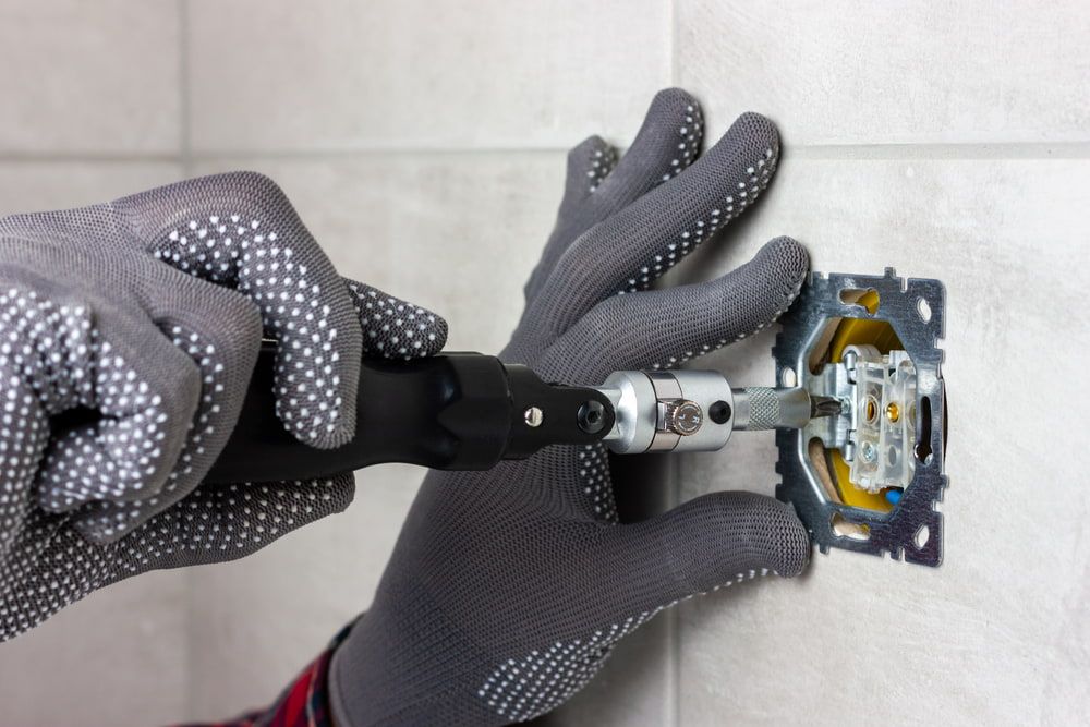 A Person Is Installing A Light Switch On A Wall — Robon Electrical In Holloways Beach, QLD