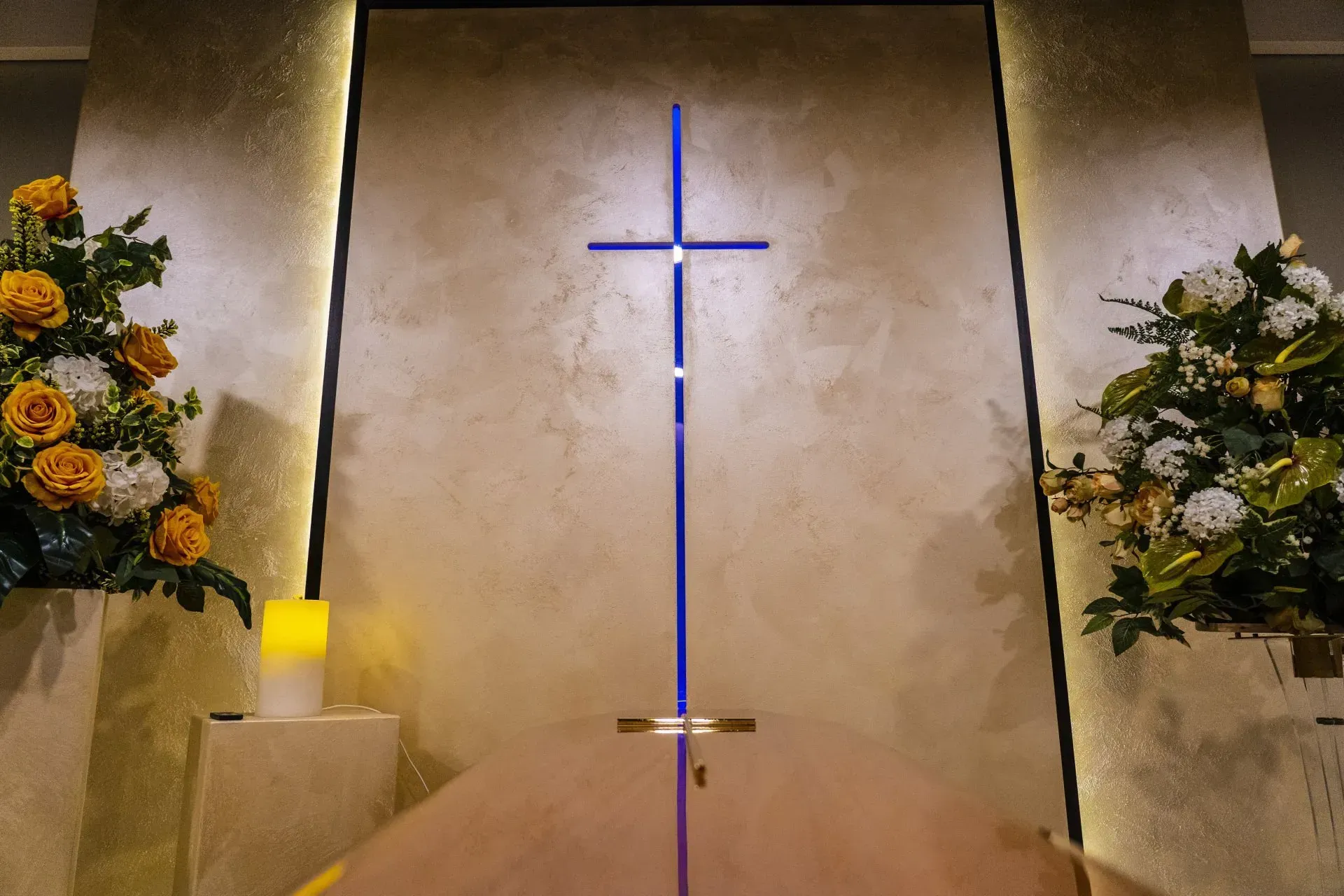 Una chiesa con una croce sul muro e fiori sul pavimento.