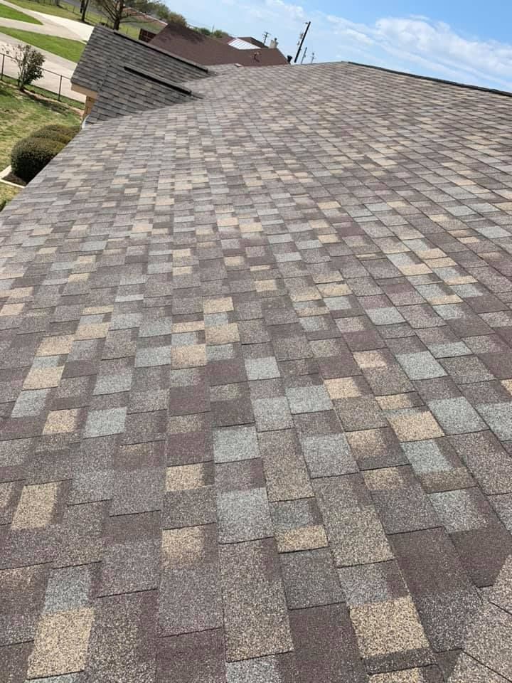 Close-up of a brown asphalt shingle roof on a house, with varying shades of brown and gray.