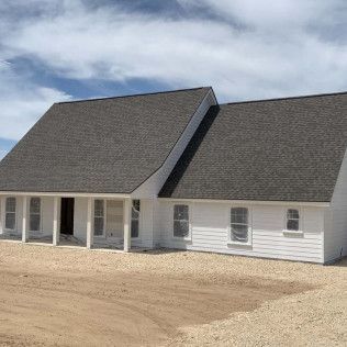 White house with gray roof under construction; exterior view.
