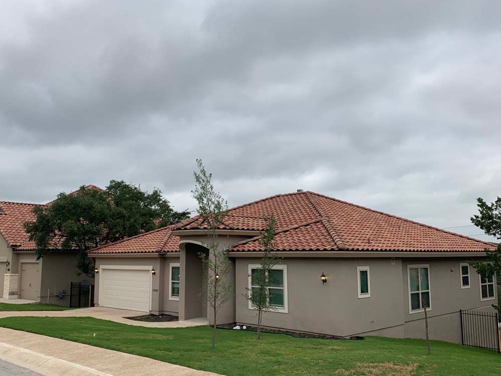 Tan stucco houses with orange tile roofs under a cloudy sky.