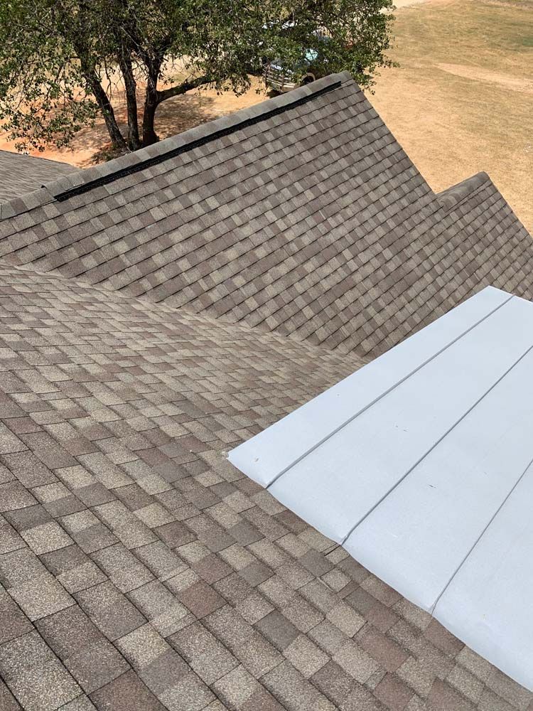 View of a shingled roof with a white, rectangular structure on its side.